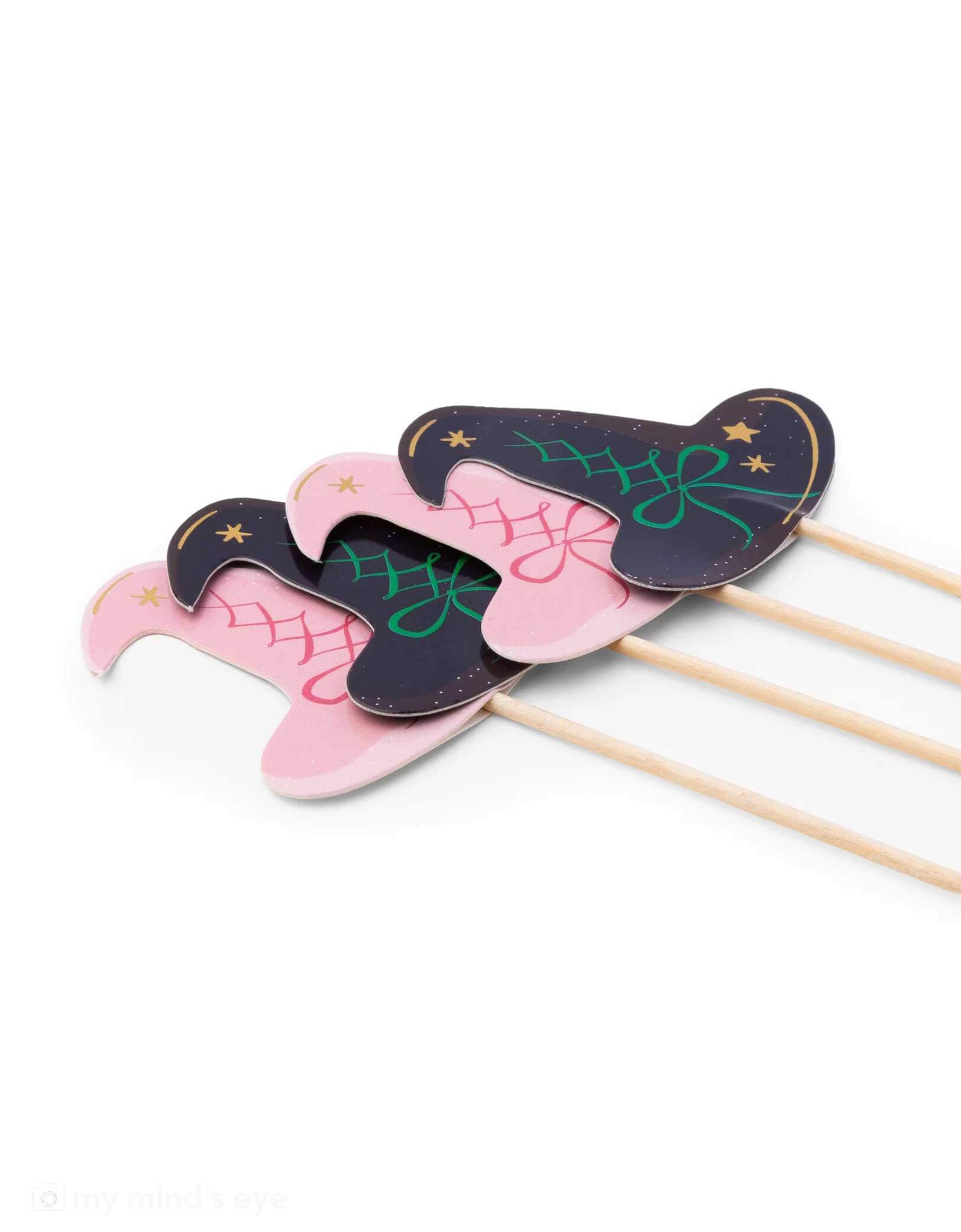 Four witch hat cupcake toppers on sticks, two pink and two black with green accents from Momo Party, on a white background. These toppers are perfect for a Wicked themed party.