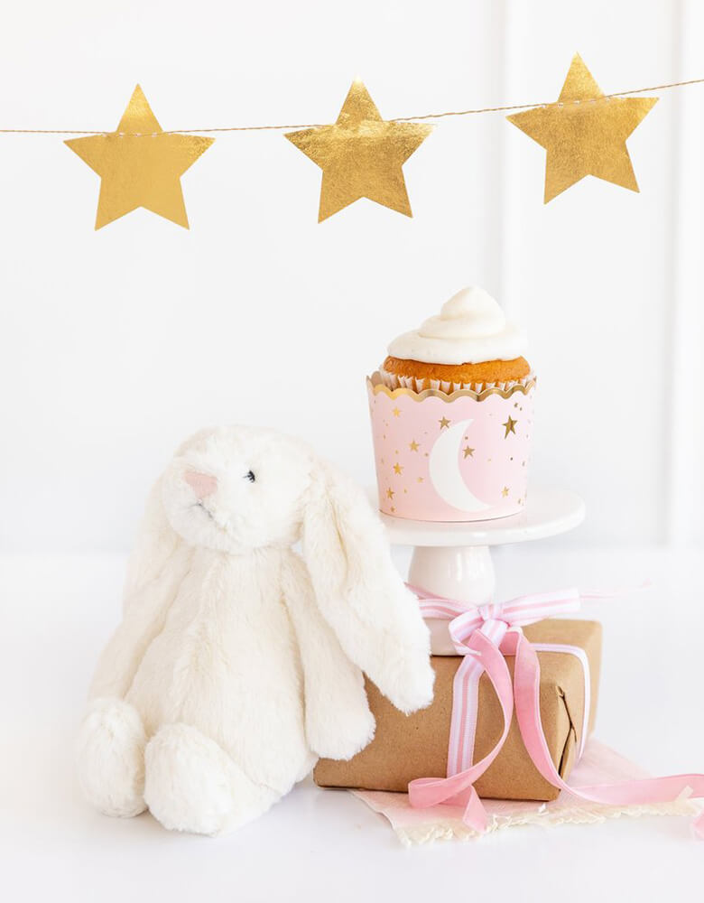 My Minds Eye Baby Pink 5 oz Food Cup with a cupcake next to a white stuffed bunny decoration with gold star party banner on the wall for a baby girl shower