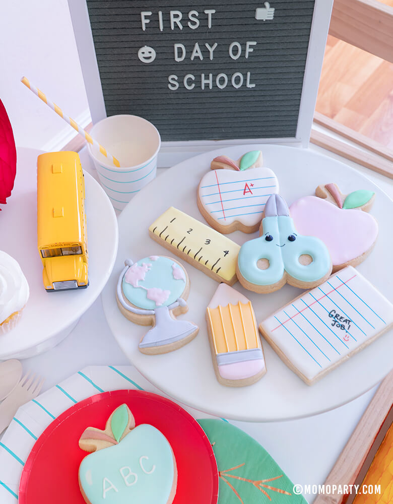 Momo party - Morden Back To School Party Table Ideas with Back to school themed cookies, Oh happy day Cherry Red side plate, Aqua Striped Large Plates and cups, Leaf Napkins, Letter board with "First Day of School" sign, cupcakes, and school bus toy on cake stand as tableware