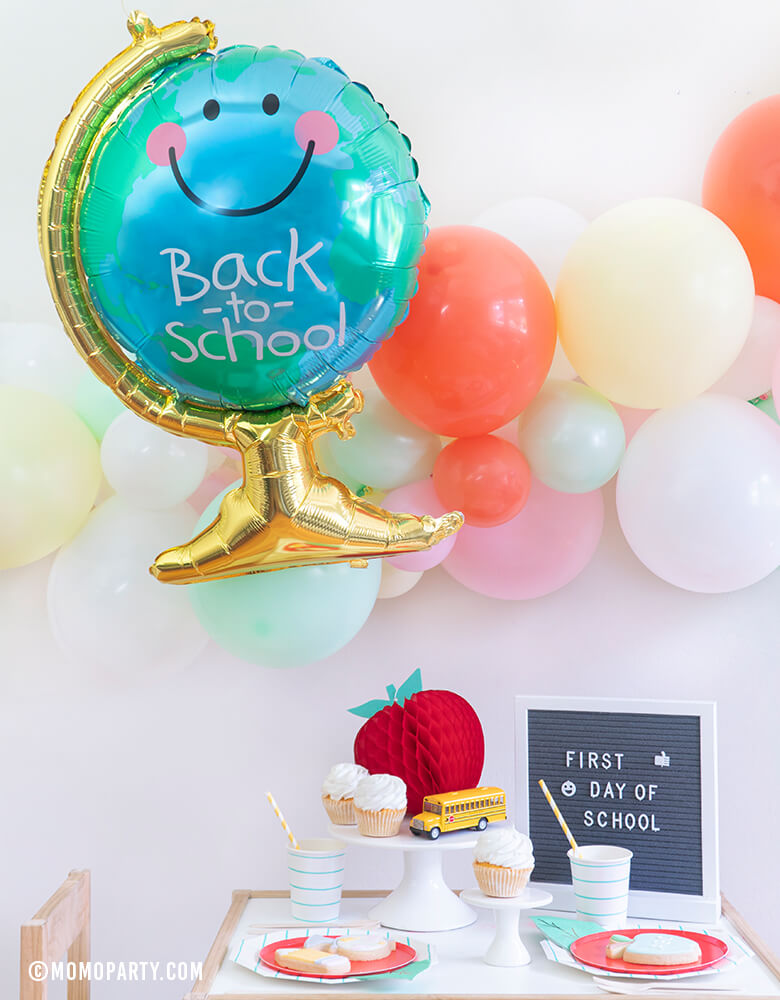 Momo party - Morden Back To School Party inspiration with Anagram Back To School Globe Foil Mylar Balloon, 6ft long Balloon Garland Assorted in Pastel Yellow, Pink, Mint, Carol, White Latex Balloon for Backdrop decoration, Letter board with "First Day of School" sign, Oh happy day Cherry Red side plate, Aqua Striped Large Plates and cups, Leaf Napkins as tableware, Honeycomb Apple, cupcakes, and school bus toy on cake stand 