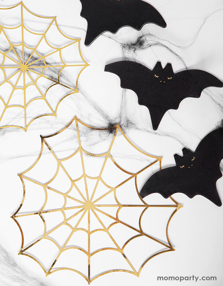 A marble tabletop with Party Deco Bat Napkins and Gold Spiderweb Decorations. Table set up for a halloween party