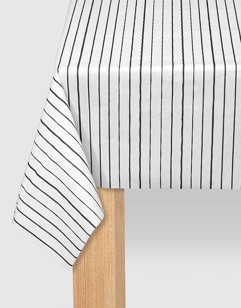 Coterie - Black Pinstripe Tablecloth. 8.5ft x 4.5ft. Made from a super soft paper that Recyclable and compostable, this modern black pinstripe tablecloth does double duty: protecting surfaces and adding a great design touch to your tablescape.