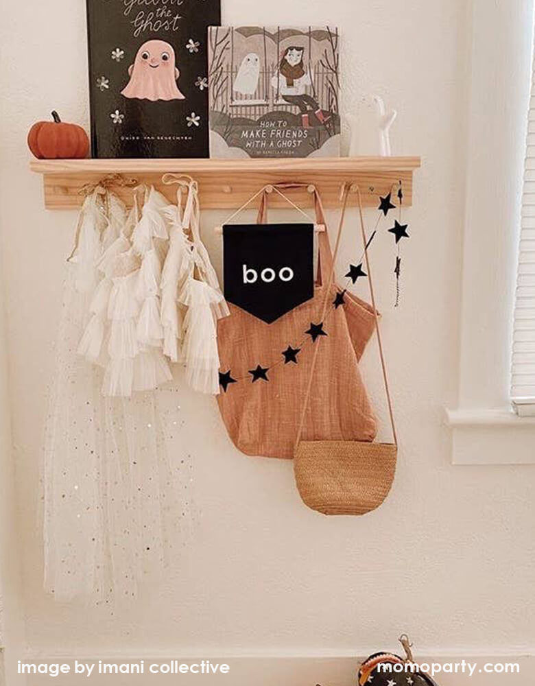 Kid's room wall shelf hanging with girl's beautiful tutu dresses, a black canvas Boo hang Sign, black star banner, Woven bags. And a pumpkinhalloonween books, a cute white ghost figures. These modern unique halloween product are so fun for your little one's room decoration, party decoration, and instagram worthy photos for you halloween celebration memories. Sell from Party Boutique Online at momoparty.com