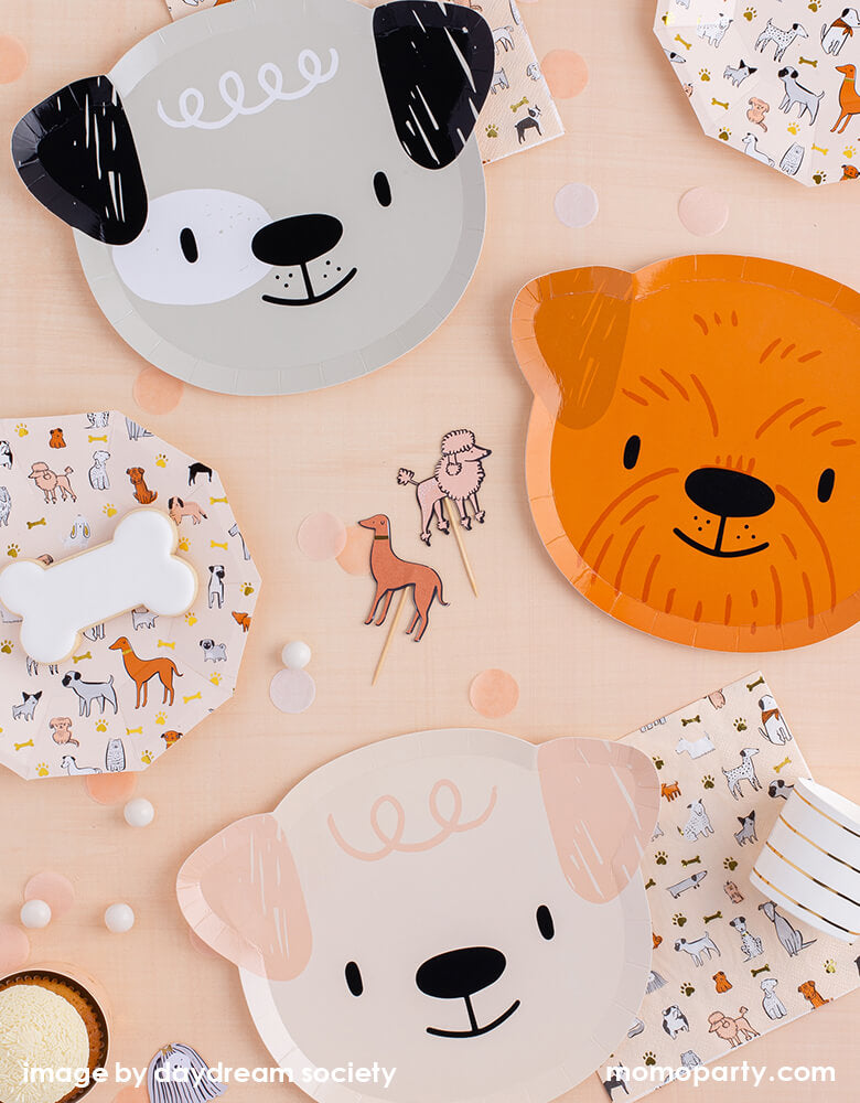 Party Boutique - Daydream society- Bow Wow collection. Featuring cute dogs head shaped paper plates of 4 designs in morden illustrations with a warm neutral color palette, with wooden utensils, light colored confettis on top of Natural Cabin Check Tablecloth. These modern Dog Birthday Party Supplies are perfect for a dog lover, a dog themed birthday party, Let's Pawty birthday party, adorable puppy themed party