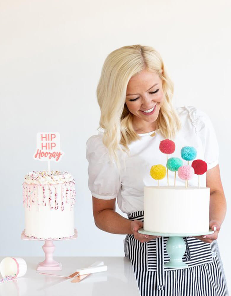 Courtney holding her cake dressed with the Pom Pom Cake Toppers by Mind Mind's Eye
