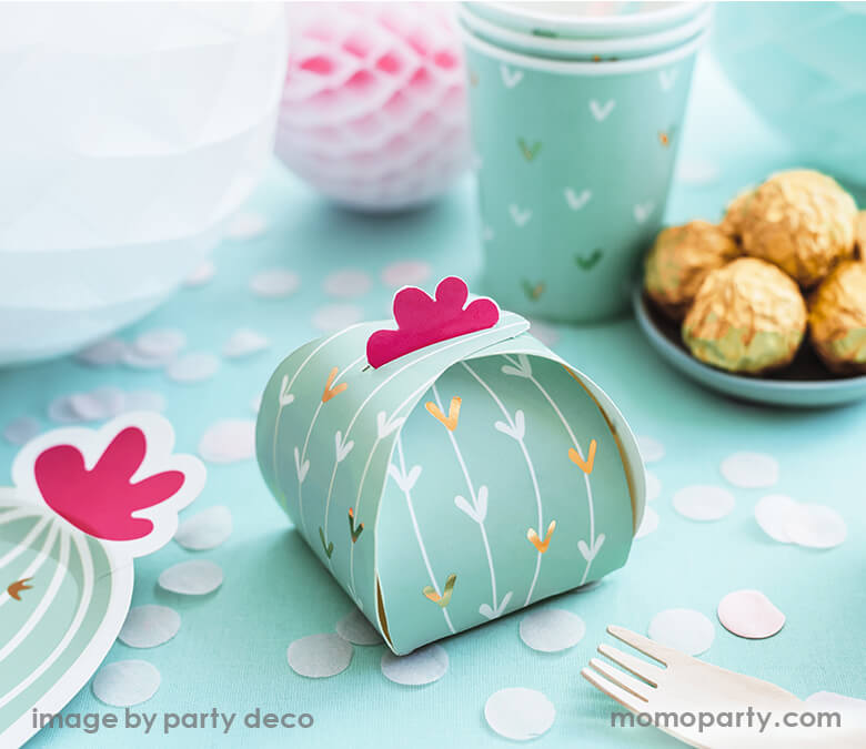 close up of fiesta cactus themed party tableware with mint cactus party box and confettis, a small plates of chocolates, homecomb, and cactus cups