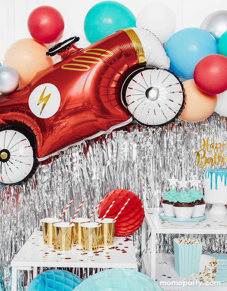 Car themed birthday party with Party Deco - 36inch Car Foil Mylar Balloon, with a lighting icon on it's red car body with gold foil details. red, mint, blush and red balloon garland, silver curtain, red honeycomb, gold cups with red stripe party straws for a race car themed birthday party