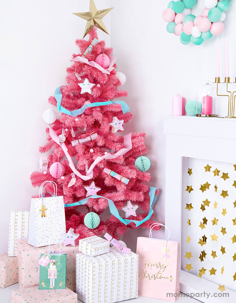 Holiday home decoration with a Pink Christmas tree full with cute ornaments and Party Deco Christmas Gift Bags and gift boxes under the tree. These 3 designs party bags with gift bag shaped gift tag on the pink nutcracker illustrated green bag, gingerbread man gift tag on the sprinkles white bag, and pink ballerina gift tag on the Pink bag with gold foil Merry Christmas sign.