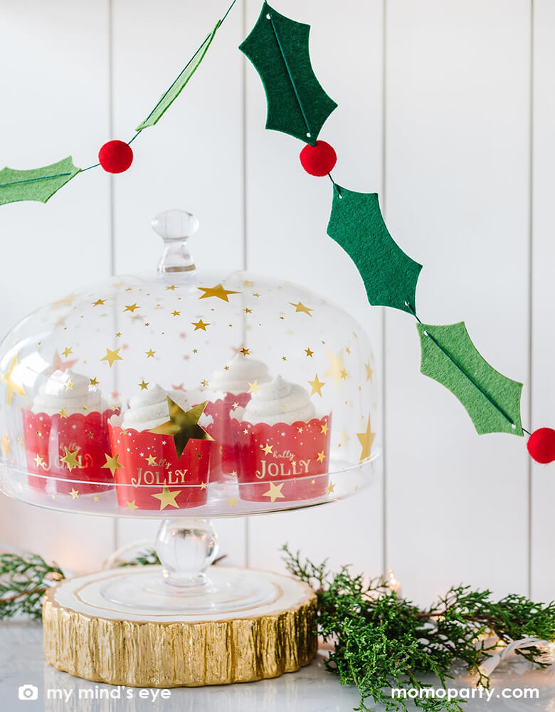 Christmas sweets with christmas jolly food cups in a Glass Dome with gold stars, there are fresh Pine branches next to it, and My Mind's Eye Holly And Berries Felt Banner with 26 Holly leaves and 10 felt balls hanging on the top, it makes modern and cozy Christmas gathering. Perfect to line the food table at your Christmas party. Adorn your Christmas tree with this festive felt garland.