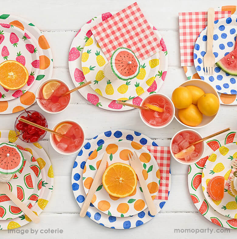 Summer Fruity Party table filled with layered Fruit Punch Large and Small Plates, red-and-white gingham Summer Picnic Small Napkins, wooden cutlery, soda with sliced lemon in cups, orange, lemon, watermelons on the plate with watermelon umbrella topper. These modern designed Bright and fun partyware are perfect for any summer parties