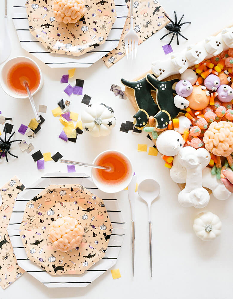 A fun Halloween kids friendly party table featuring Daydream Society's Hocus Pocus tableware collection and a fun trick or treat themed dessert board with Halloween themed sugar cookies, candy corn, pumpkin gummy, ghost shaped meringue and peeps