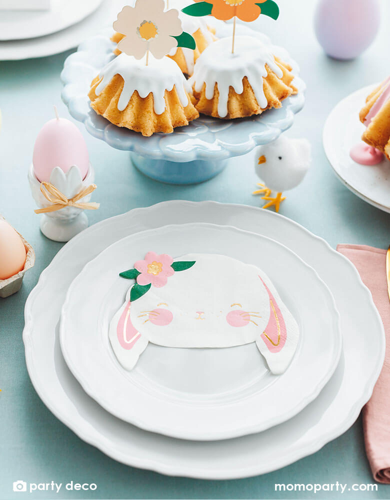 An adorable tablescape featuring Momo Party's floral bunny napkins by Party Deco on two sets of white plates, around them were Momo Party's 2.75" Easter chicks decorations and Easter egg shaped candles. On the table there's some bundt cakes topped with floral cake toppers - all make a beautiful Easter brunch table.