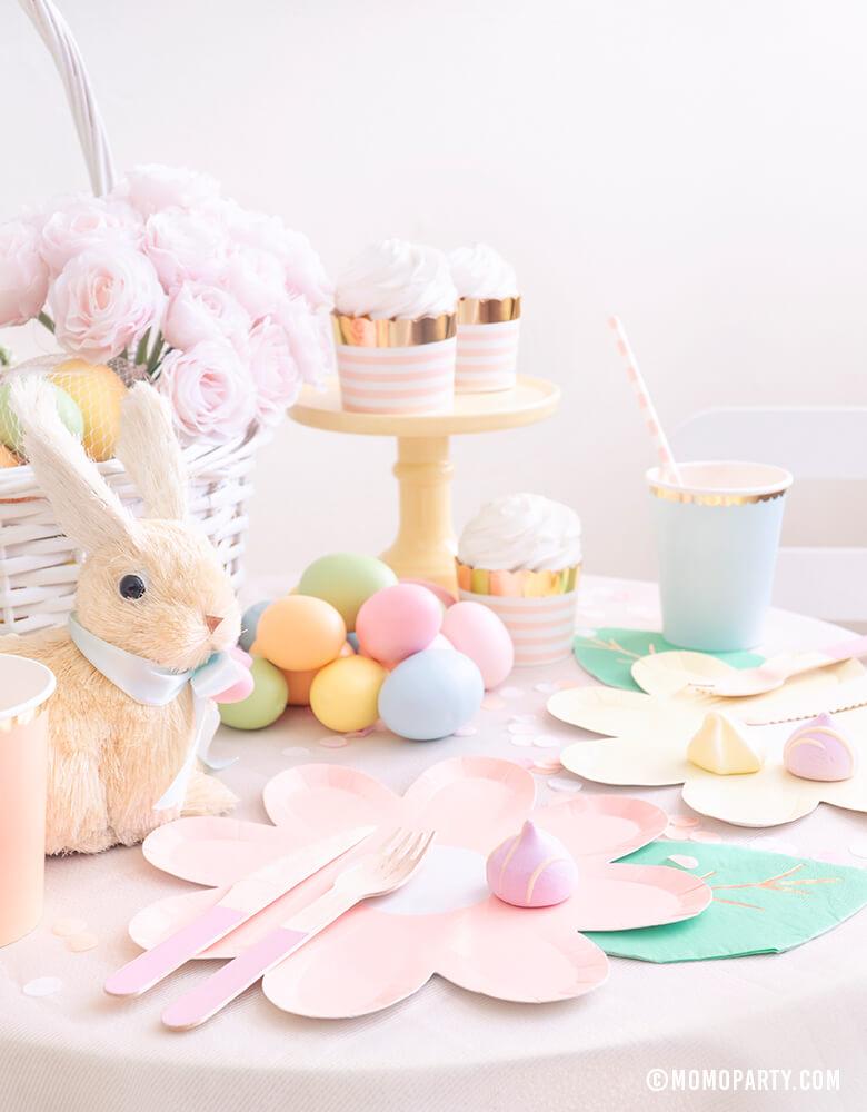 Modern pastel Easter Party dessert table with Pastel Daisy Large Plates, Pastel Cups, Leaf Napkins and Easter Basket and pastel eggs, bunny decoration, and sweets