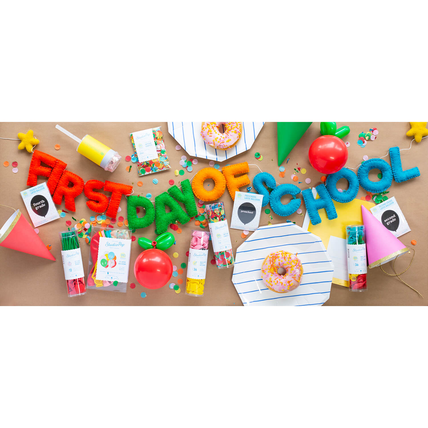 A back to school first day of school party table with Studiopep first day of school felt banner in multiple bright and vibrant colors and Apples Balloon and themed confetti to celebrate kid's start of a new school year
