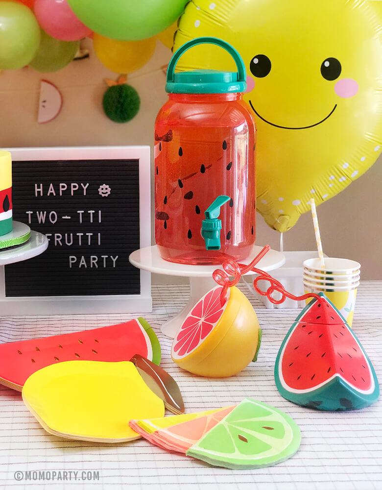 Summer Bright Fruit themed party table decoration with watermelon and lemon paper plates, pink and mint circus napkins, Lemon paper cup, Sunnylife citrus and watermelon sippers, and big lemon Foil Balloon and letter board with "happy two-tai Fruity Party" sign
