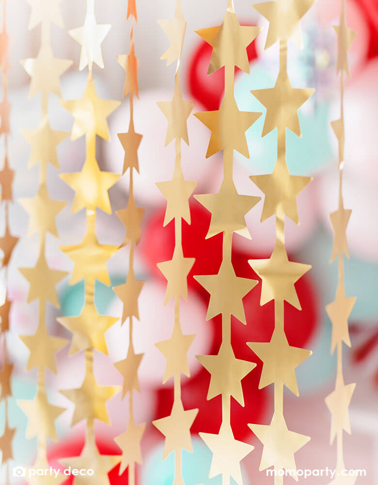 Momo Party's Gold Star Curtain by Party Deco with colorful balloon garlands in the back., it's a great decoration for your Holiday party, graduation celebration, or a Twinkle Twinkle Little Star themed baby shower.