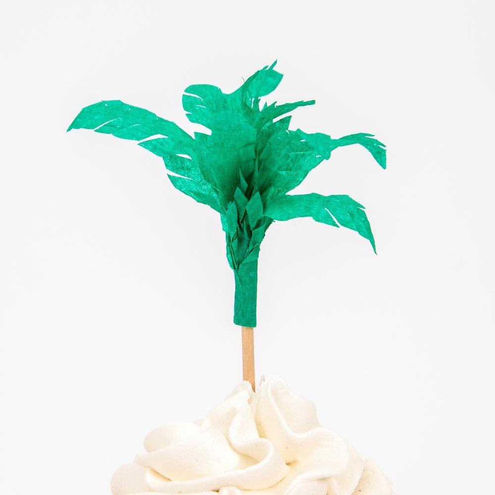 Close up details a cupcake decorated with paper palm trees cupcake topper from Meri Meri Dinosaur Kingdom Cupcake Kit
