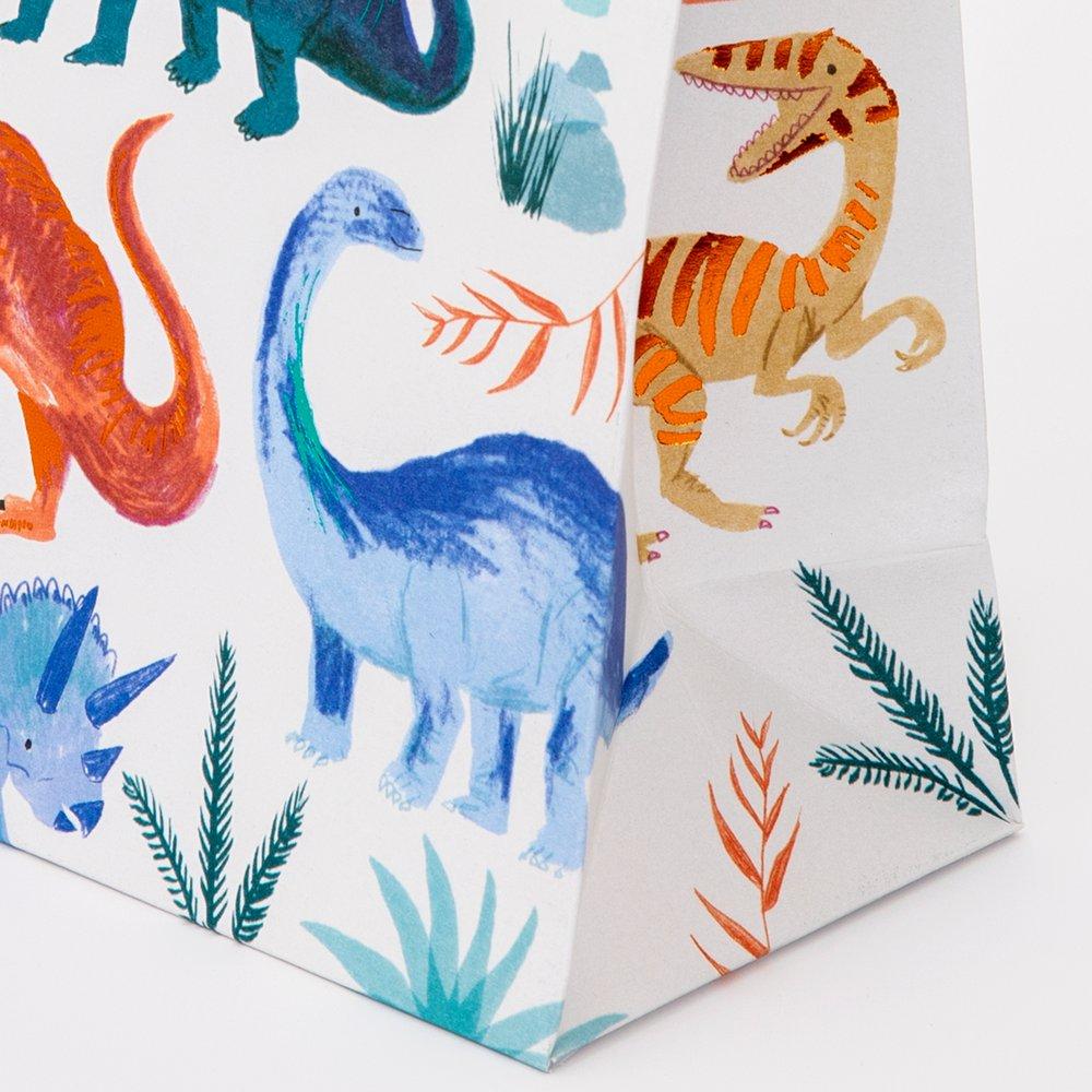 Close up details of Meri Meri Dinosaur Kingdom Party Bags with twisted paper handles and beautifully illustrated dinosaur design