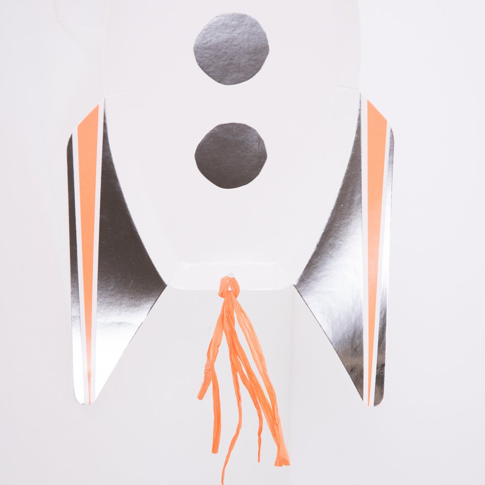 A detail looks of bottom design Rocket Plates by Meri Meri. These awesome rocket shaped plates are an amazing way to decorate a space party table to delight little astronauts. They are crafted from high quality card, Made from eco-friendly paper, in a rocket shape design and Shiny foil detail, Orange raffia tassels, so are perfect to heap with space treats too.