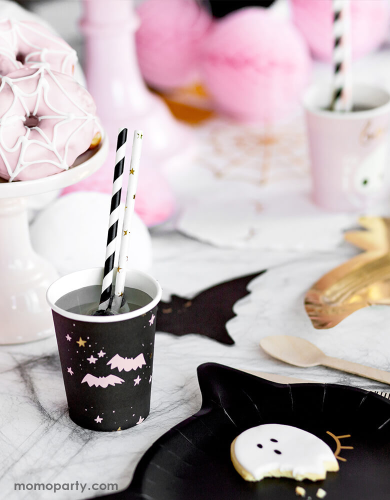 Party Deco Halloween Boo! Paper Cups, with a pastel pink bats and stars in a black cup with Black stripe and Gold star party straws, with Ghost cookies on a Black Cat paper plate, Black Bat napkins, and pink spider donuts in a cup stand for a Spooky pink Halloween party!