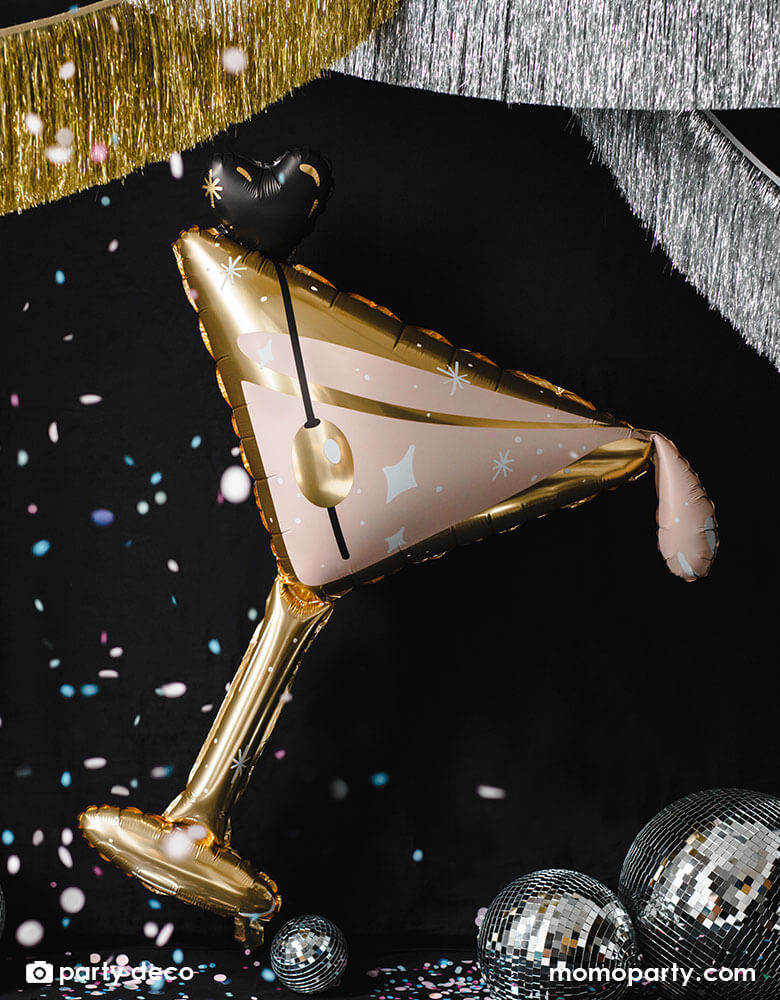 Momo Party's 34.5" Martini Glass Shaped Foil Balloon in rose gold and gold accent in front a disco ball decoration and gold and silver tinsel garland, makes a perfect decoration for a New Years Eve countdown celebration.