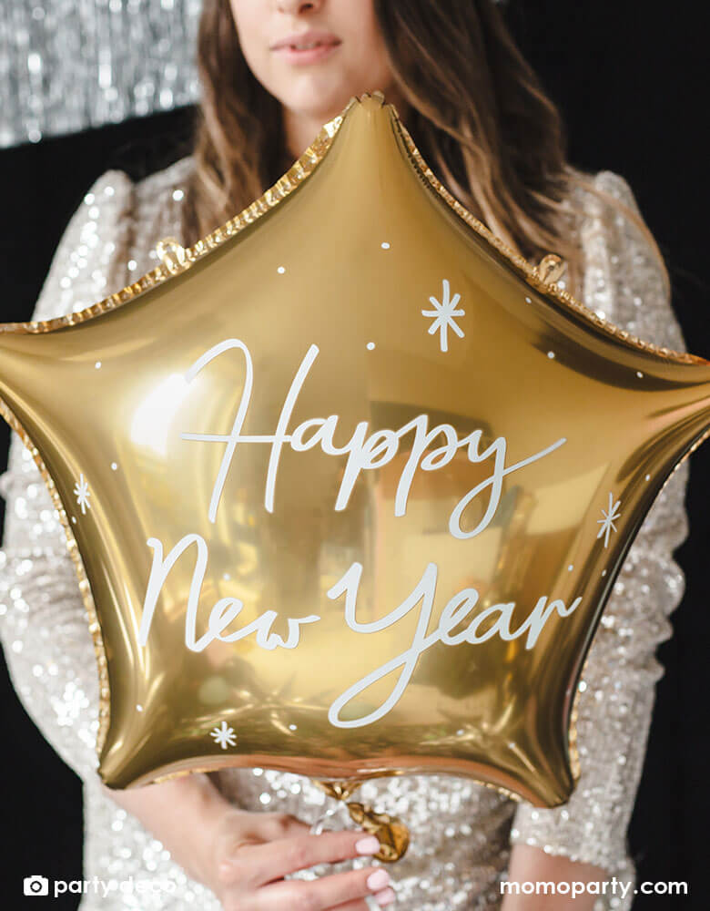 A girl in her sequin dress holding Momo Party's gold star shaped foil balloon and celebrate New Year