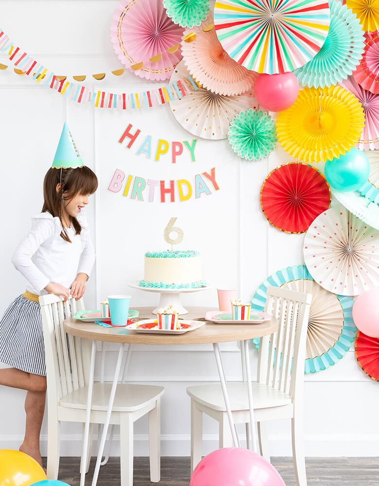girl's 6 years birthday party table set up with colorful letters Happy Birthday Banner, cake, backdrop decorations