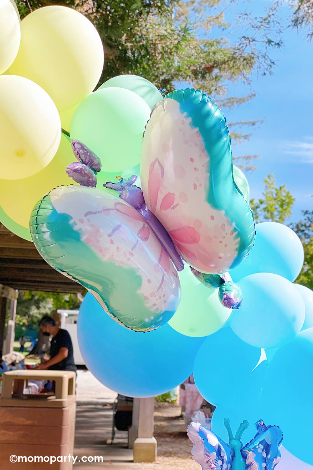 Momo Party's 29" Flutters Butterfly Foil Mylar Balloon on a pastel rainbow balloon arch in a girl's fairy themed birthday party.