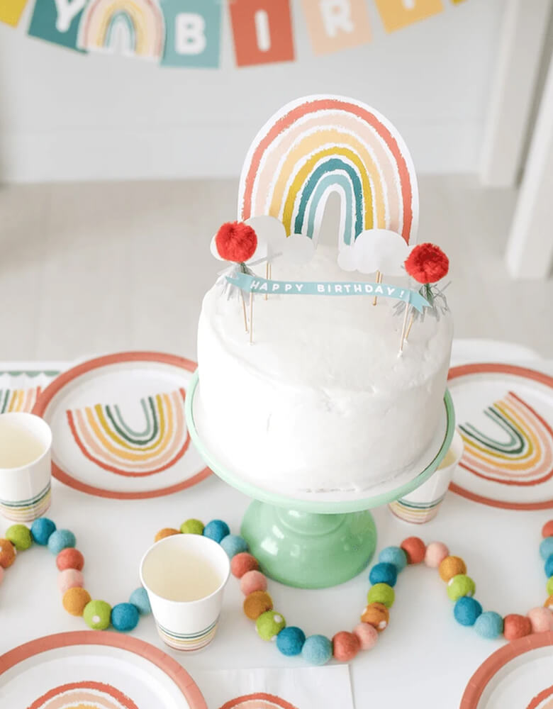 Lucy Darling Little-Rainbow-Party-in-a-Box_Rainbow-toppers-on-a cake with rainbow themed tabletops around