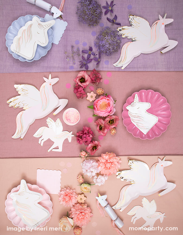 Pretty in pink unicorn party on a layered purple, coral and pink table cloth, mixed with Meri Meir Winged Unicorn Plates and Napkins, Magical Unicorn Plates, Multicolor Simply Eco Plates in pink, lilac, light pink, and colorful flowers as centerpiece