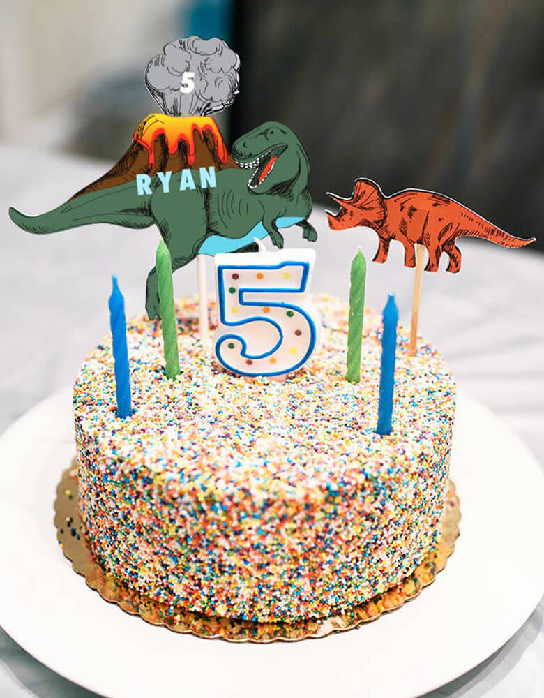 A dinosaur themed birthday cake topped with Merrilulu's custom dinosaur cake toppers and birthday candles