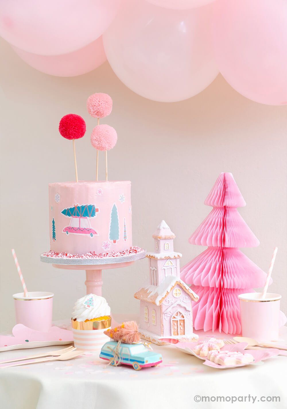 Momo-Party-Holiday Set up with Pastel pink buttercream cake decorated with Let's Get A Tree! Cakescape Edible Stickers of christmas tree on a truck, snowflakes stickers. Cake By Courtney Pom Pom Cake Toppers, Light Pink Honeycomb Paper Christmas Tree, a snow pink house decoration, pastel mint car carry a pink tree ornament, cupcake in the Blush Striped Food Cup, fa la la tree plates on the table for a modern cute sweet cozy look holiday celebration