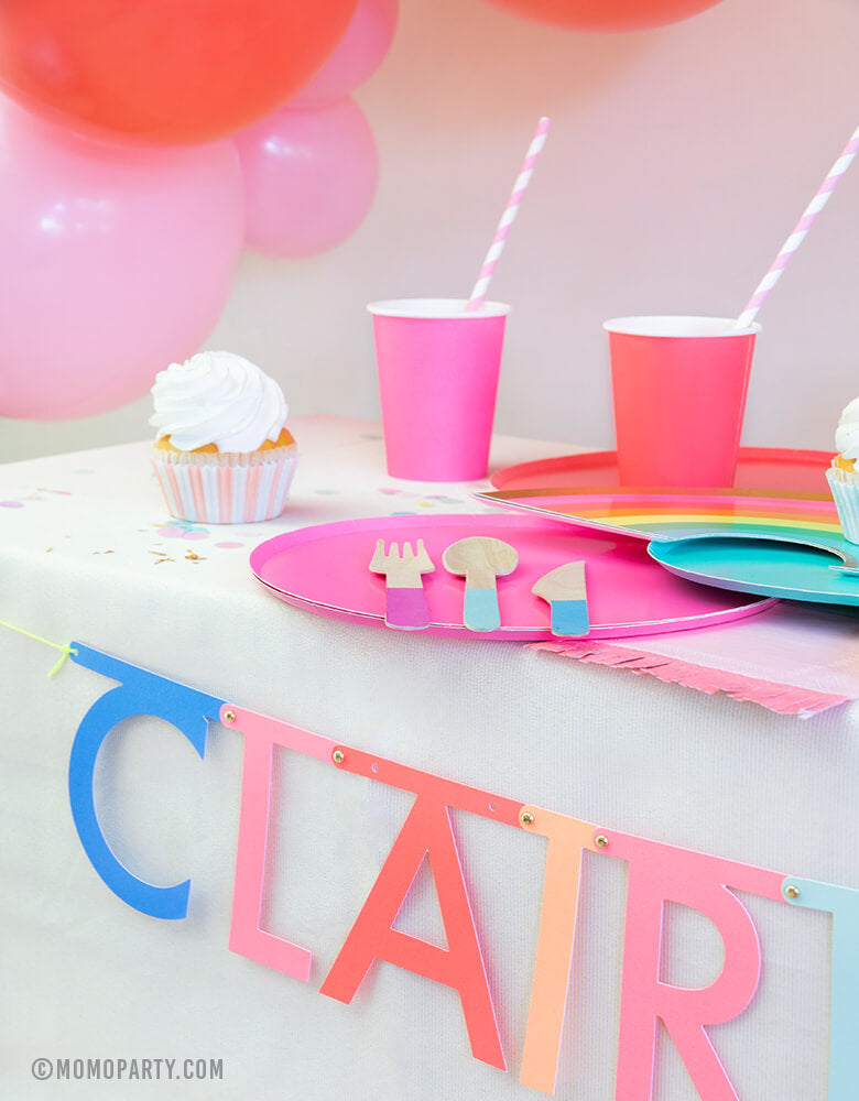 Rainbow party table look with Oh happy day rainbow plates, cups, Meri Meri Multicolor-Make-Your-Own-Letter-Garland-Kit spelling of "Claire is 6" for a girl's rainbow birthday party