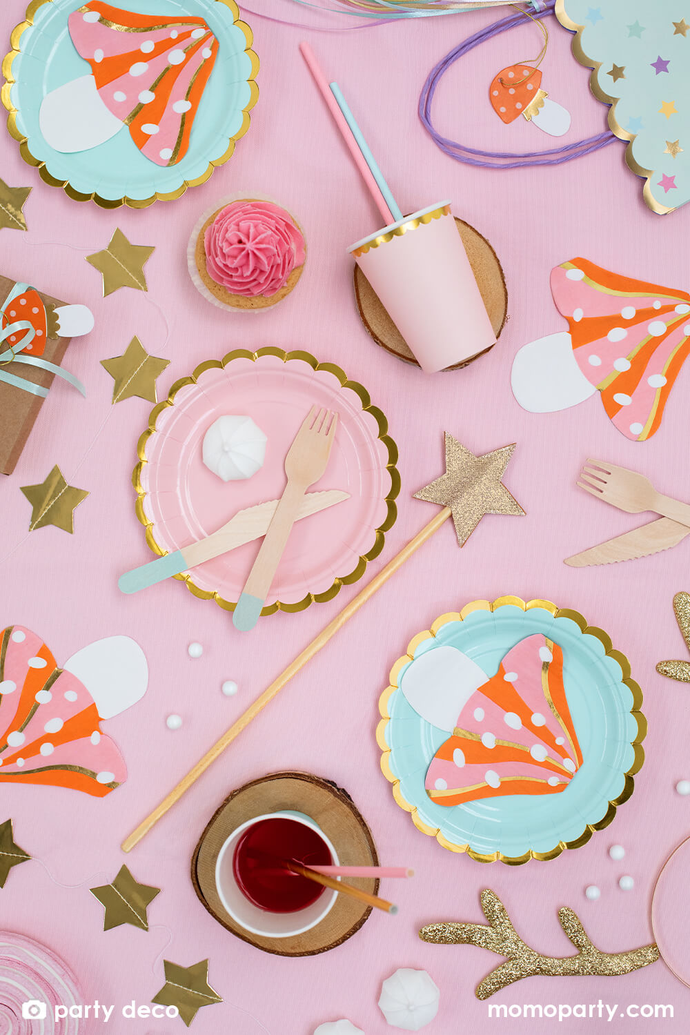 Holiday table set up with Pink and Mint scallop plates layered with Party Deco - Mushroom Napkins, cupcakes, gold star garland,  shining star wand, pink cups on a pink table cloth. These whimsical mushroom napkins are perfect for your woodland or forest themed celebration.