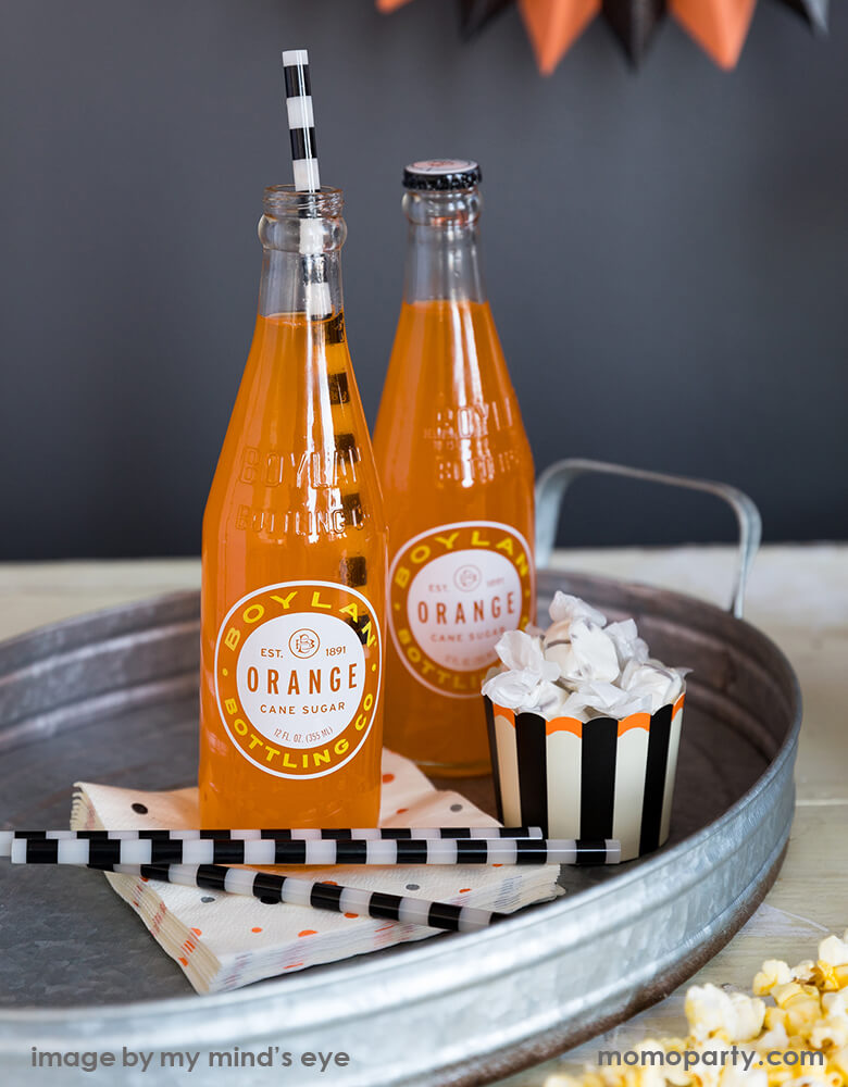 Close up look of Classic halloween party table with candies in the My Minds Eye Vintage Halloween Food Cup, Boylan orange juice in the glass bottle with vintage halloween reusable straws, vintage halloween cocktail napkins in the Galvanized metal tray
