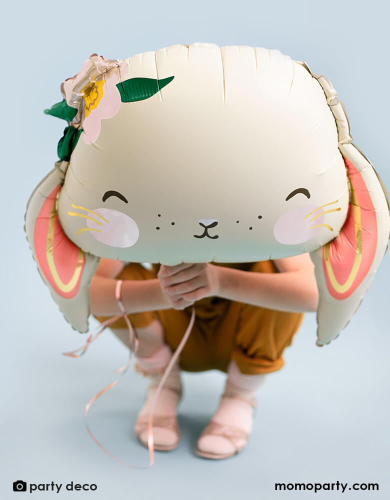 A Kid holds Party Deco's 26" Floral Bunny Foil Balloon in pretty pastel color of pale ivory, makes a great addition to your Easter celebration