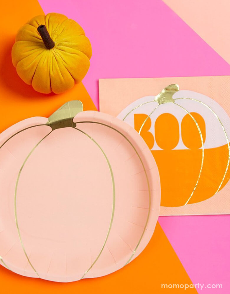Talking Tables - Pumpkin Shaped Paper Plates with Pumpkin Boo Napkins and Velvet Pumpkin Table Decoration in orange, on top of a bright pink and orange table top.  This frightfully fabulous pumpkin plates contains pumpkin shaped plates in autumnal blush shade with gold foil details. There are perfect party tablewares for autumn dinners, a Halloween party or Thanksgiving meal.