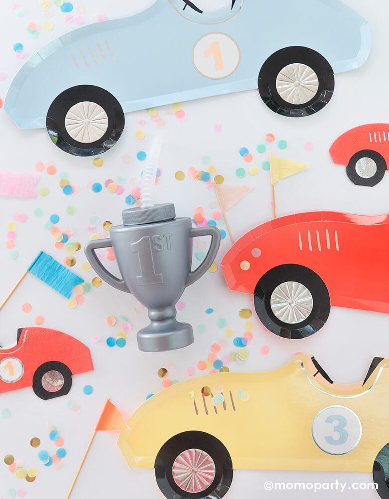 Race Car Trophy Cup among of Meri Meri race car plates and napkins, with colorful confetti and mini flag toppers, to celebrate the champion moment at a race car themed birthday party. Two fast birthday party.
