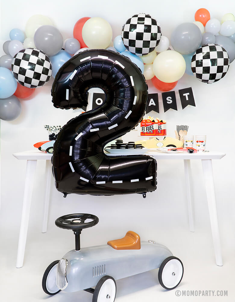 Modern Race Car party set up idea with Large Black number 2 foil balloon with decoration strip for a 2 years old Race Car themed birthday party