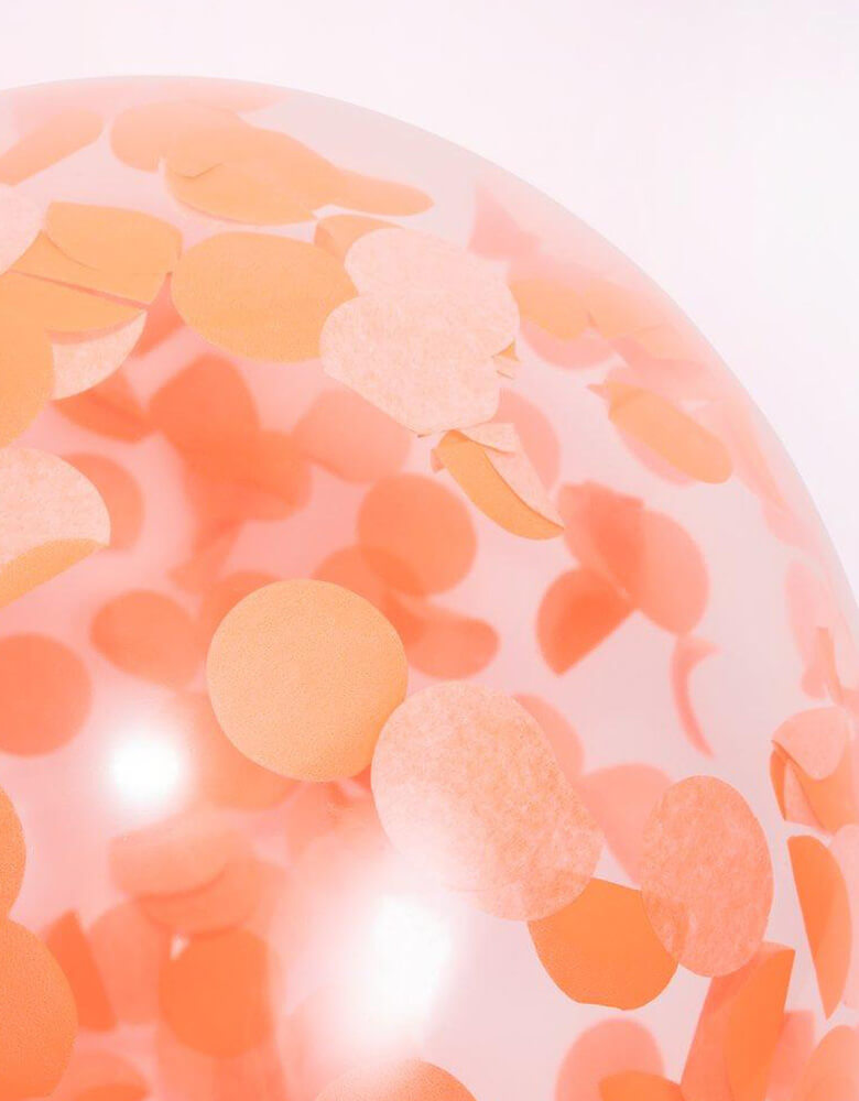 A close up of the pre-filled confetti balloons in peach orange from Meri Meri Rainbow Balloon garland Arch Kit
