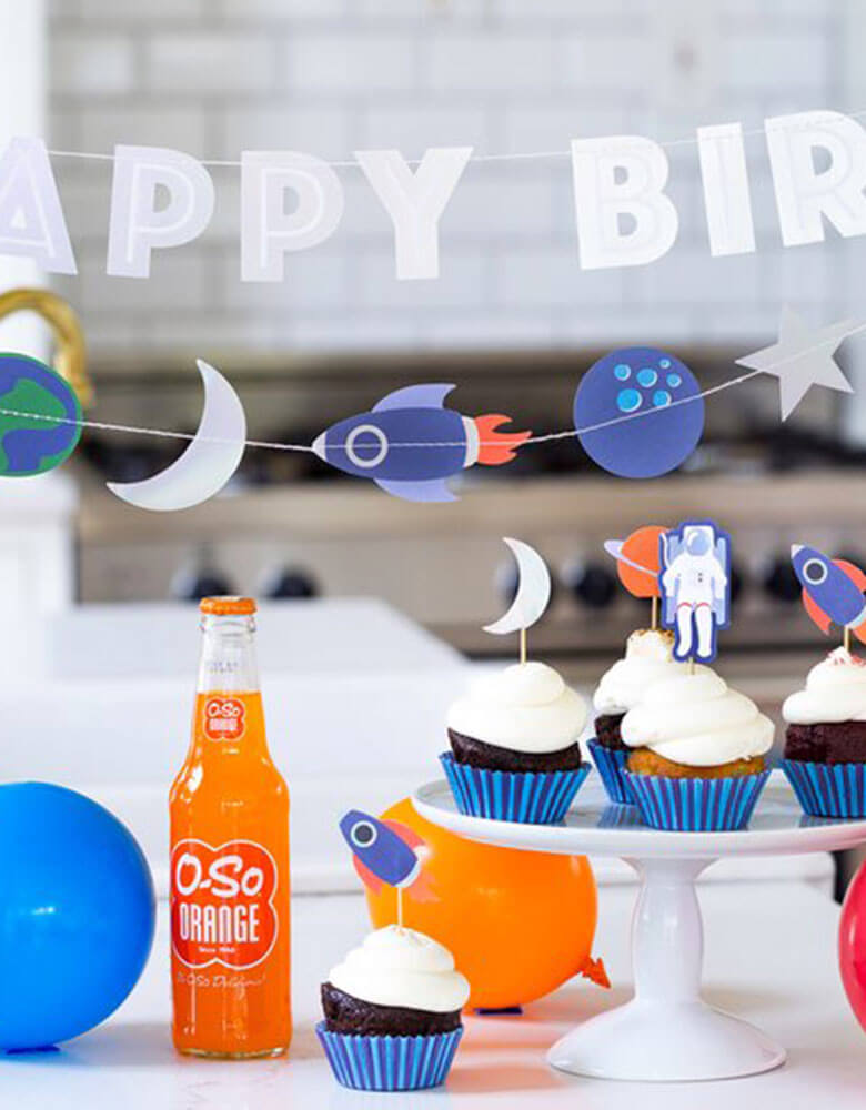 A space themed kids birthday party with My Minds Eye Rocket-Space-Mini-Banner and Happy Birthday Banner on the back with cupcakes decorated with space themed toppers