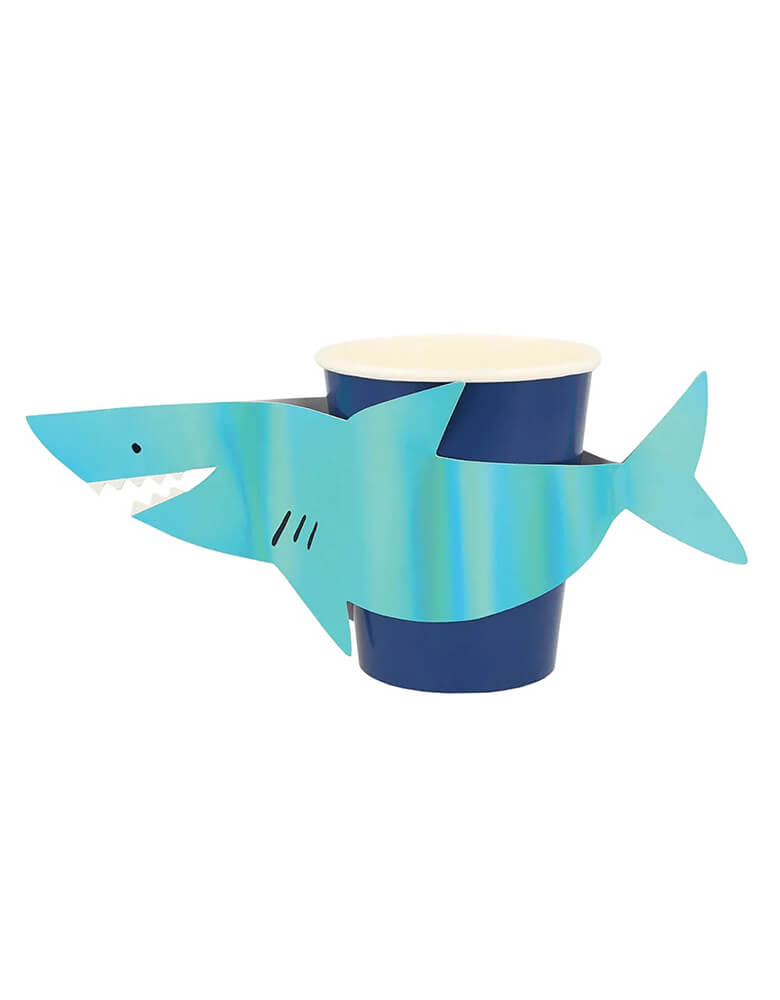 Momo Party's 9oz shark party cups by Meri Meri. Featuring Shiny blue holographic foil shark sleeves, this set comes in 8 party cups, they're perfect for kid's under the sea or baby shark themed birthday party.