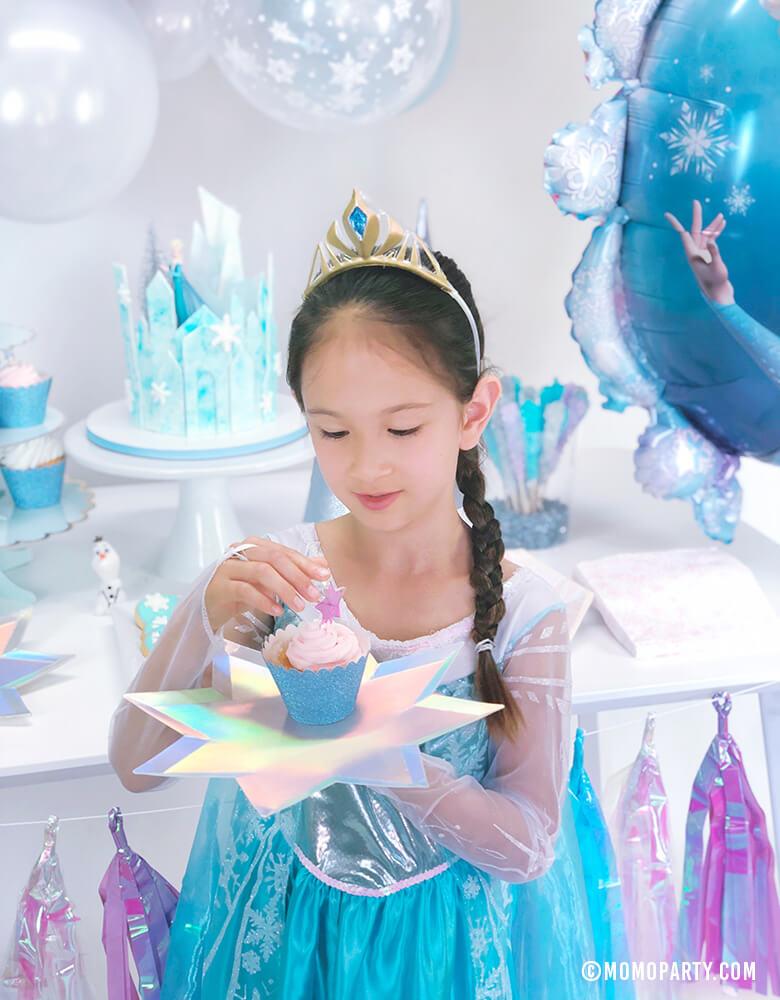 Elsa princess holding a cupcake on Meri Meri 8-point Shining Star Plates in a Frozen birthday party