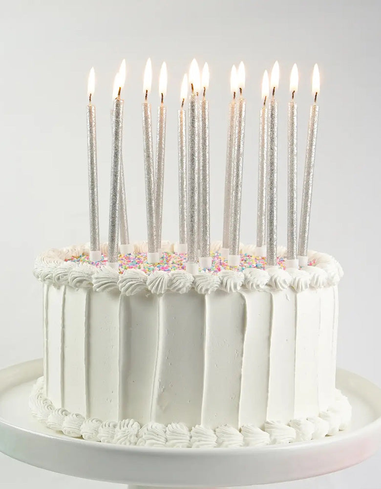 Momo Party's Tall Silver Glittered Candle Set by Party Partners on a buttercream white cake with colorful sprinkles, comes in a set of 16 tall candles, they're perfect for a kid's space or Star Wars or Frozen themed birthday party.