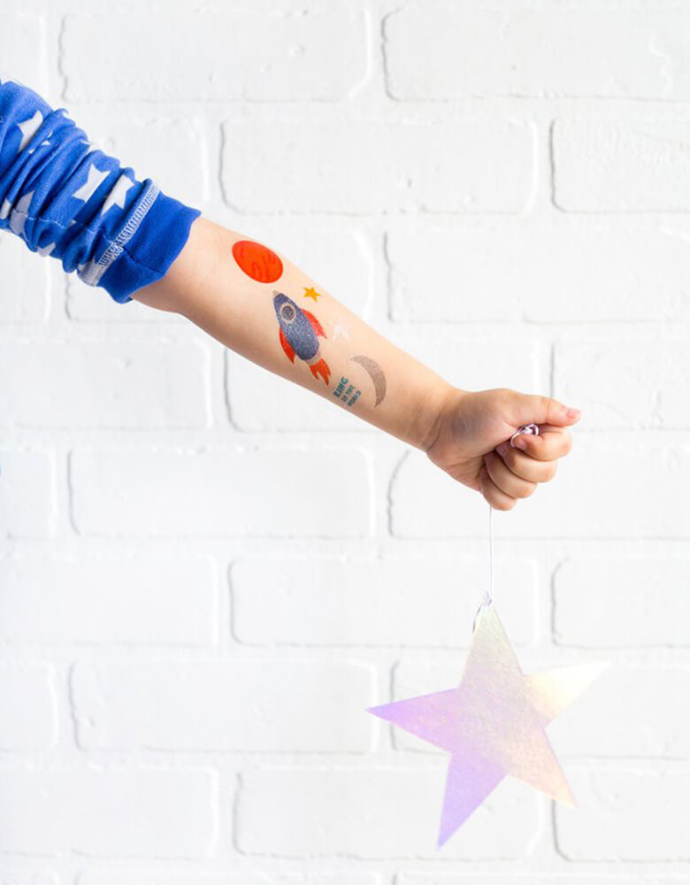 Boy's arm with My Mind's Eye Space Rocket Temporary Tattoos holding a star decoration in a space themed party