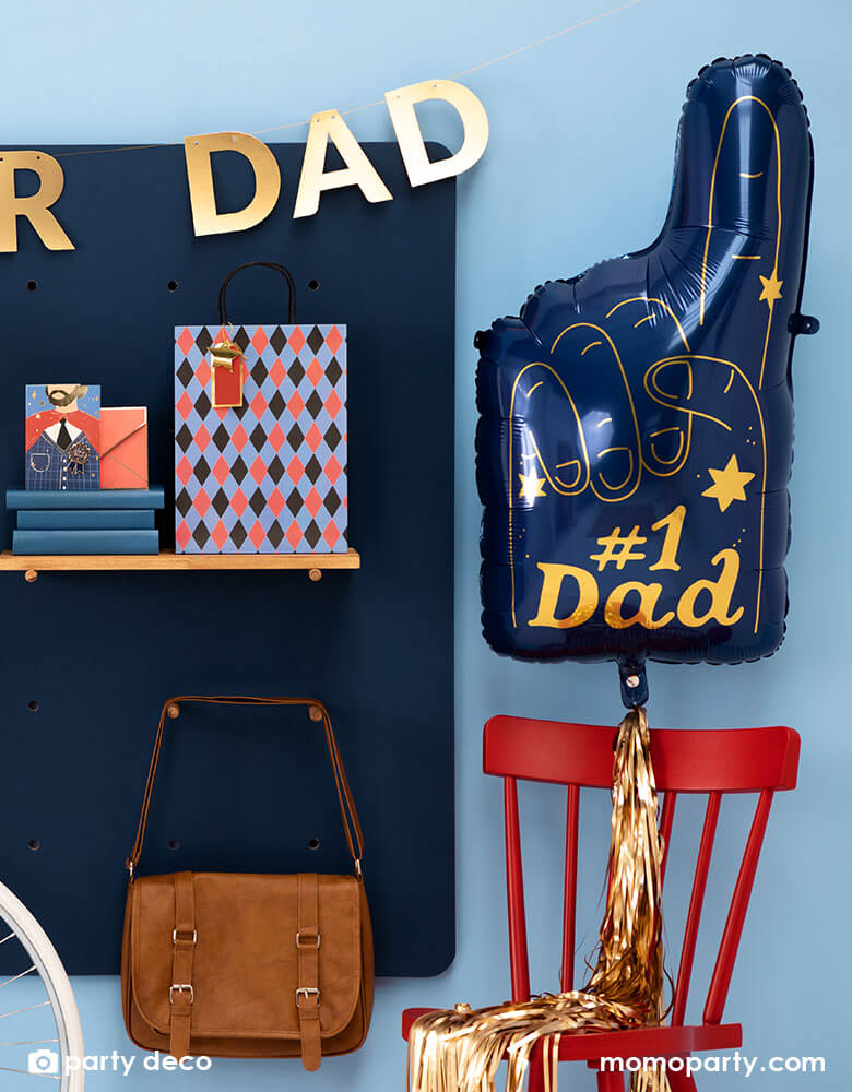 A wall decorated with cool Father's Day gifts, along side is Momo Party's 34 x 18" blue #1 Dad Finger Shaped foil balloon by Party Deco, featuring gold foil accent, it's perfect for a special Father's Day celebration.