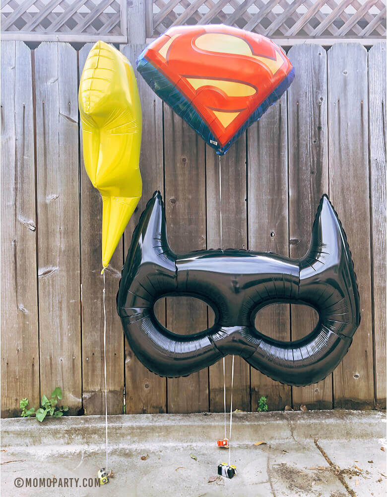 Super Hero themed birthday party decorated with Giant Bat Mask Foil Balloon, Superman Emblem Foil Balloon and Bat Mask Foil Balloon in the yard