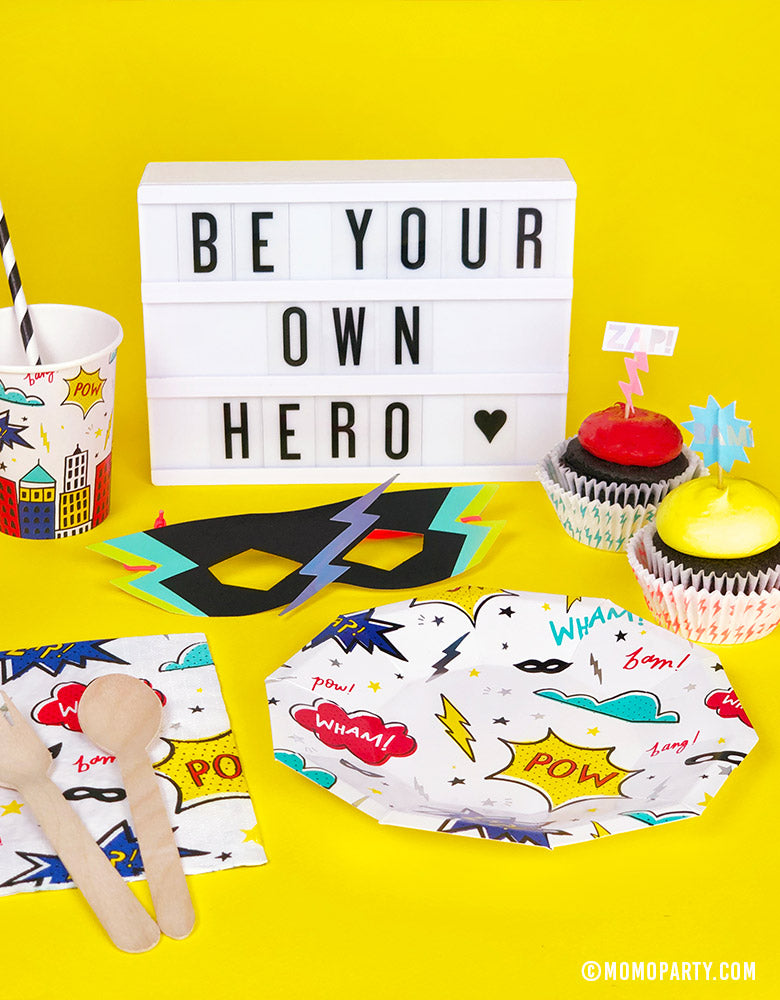 Kids superhero themed birthday party table set up with daydream society superhero plates and cups, meri meri superhero paper masks, cupcakes, Be your own hero letter sign