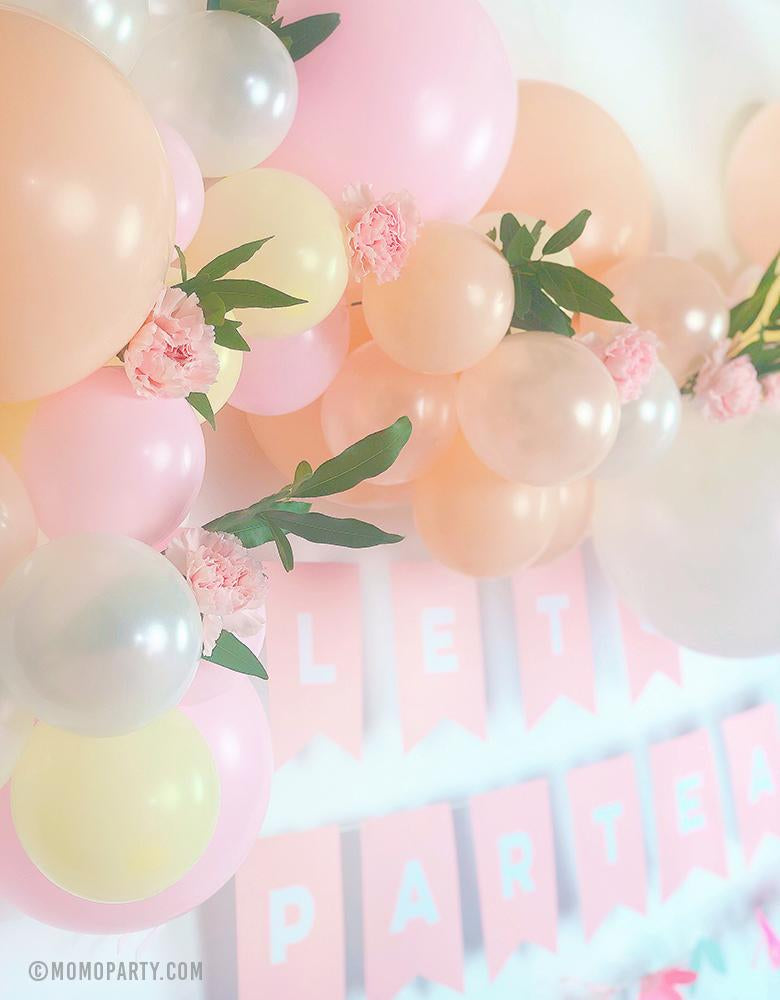 A beautiful pink blush pastel balloon garland with flower decoration and Pink letter banner of "Lets Partea" for a floral pastel tea party birthday celebration