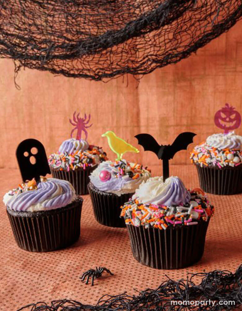 cupcake with colorful sprinkles and EM & ME - The Spooky Edition Short Sticks of acrylic sticks of jack-o-lantern, cat, crow, spider, bat and ghost shapes, these spooky short sticks are ideal for appetizer skewers, drink picks or cupcake toppers. They're made with acrylic plastic and are reusable.